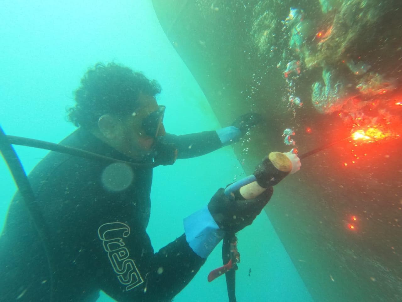 Commercial diver carrying out underwater repair work on a ship-side structure