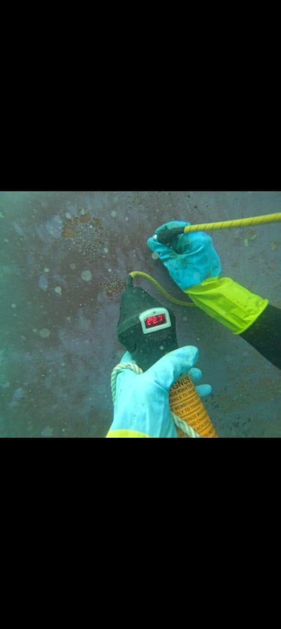 Commercial diver using an underwater thickness gauge against submerged steel