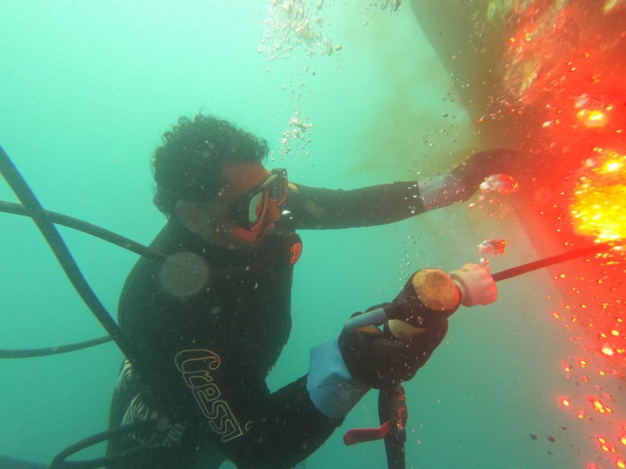 Commercial diver carrying out underwater repair work on a ship-side structure